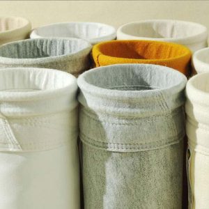 Diverses toiles filtrantes sont exposées, dont un sac filtrant pour dépoussiéreur blanc et jaune.