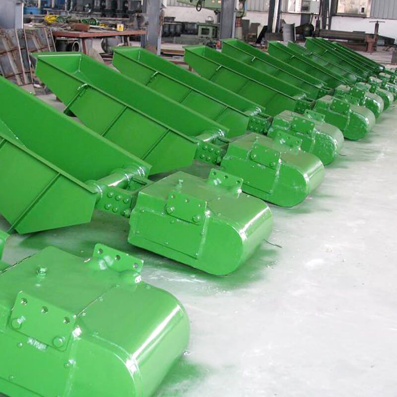 Una hilera de alimentadores de vibración electromagnética de color verde recorre la planta de la fábrica.