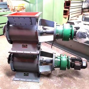 Dos válvulas rotativas apiladas en el suelo de un almacén de una fábrica, mostrando su diseño y preparación para su instalación en sistemas de manipulación de materiales.