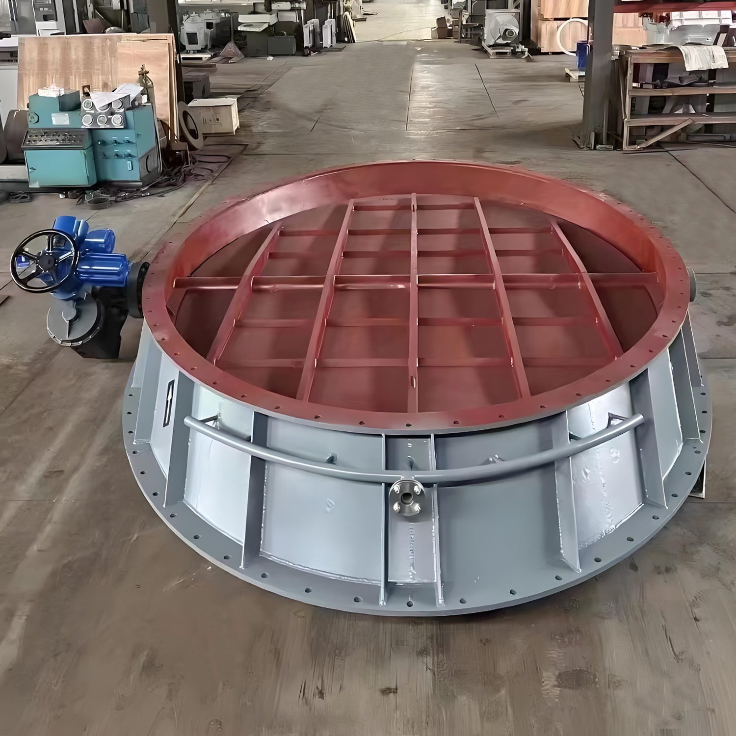 Un entorno de fábrica que muestra una gran placa metálica circular equipada con una válvula de obturación basculante eléctrica para mejorar la funcionalidad.