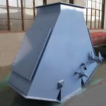 На складе стоит большой металлический станок, рядом с которым находится четырехходовой гравитационный клапан, создающий промышленную атмосферу.