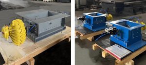 One grey pneumatic flow control valve and two blue pneumatic flow control valves are placed on pallets in the factory.